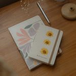 Sustainable hand-stitched notebook with vibrant floral market-inspired cover, made from upcycled newspapers, banana trunks, and dried leaves. Perfect for journaling and planning.