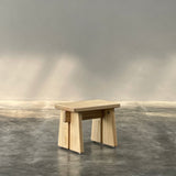 Wooden shelf against a gray wall with sunlight casting shadows.