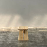 Wooden block on a gray surface with a light source casting shadows.