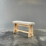 Small wooden stool with a cushioned seat on a gray background