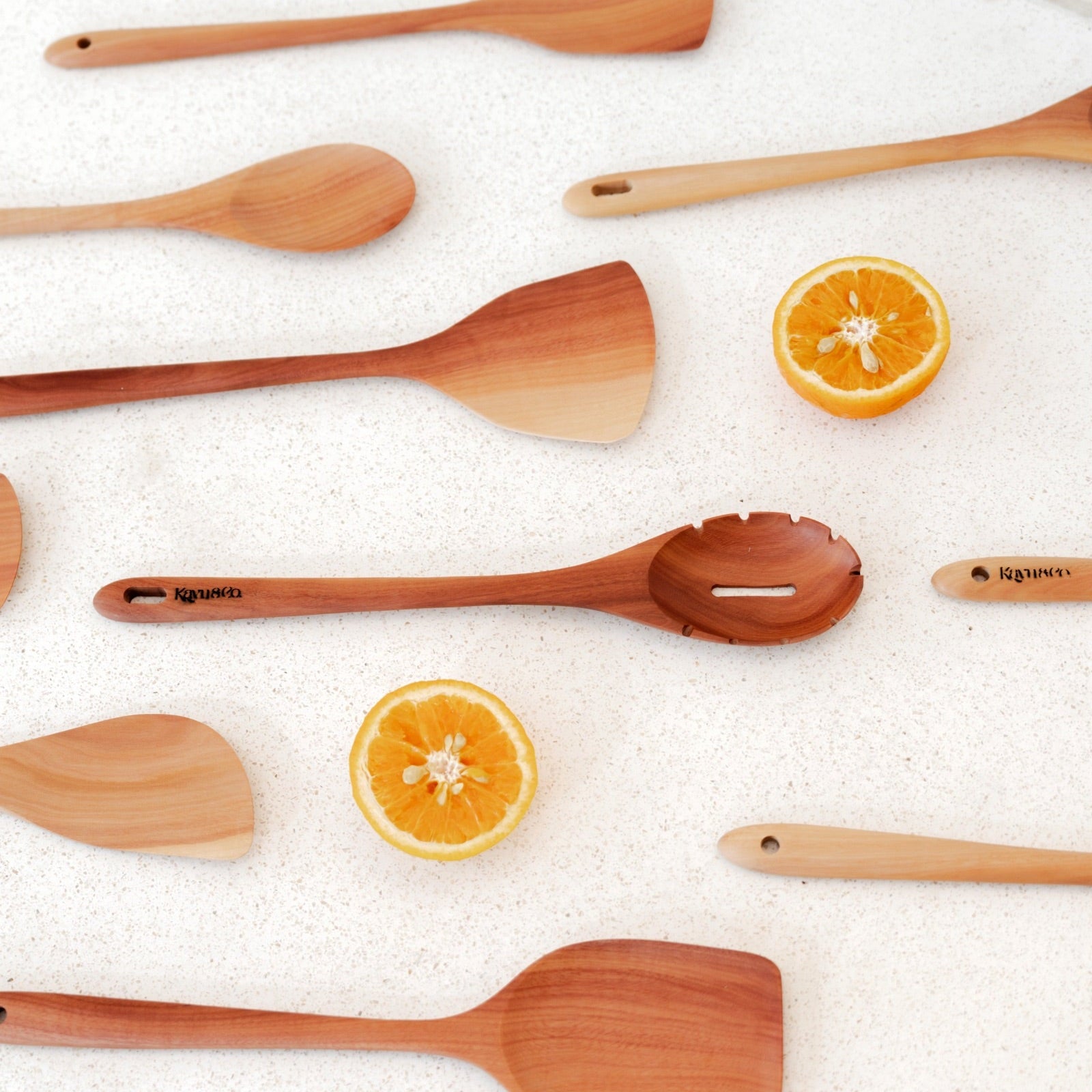 Wooden spatulas on a white surface with orange slices.