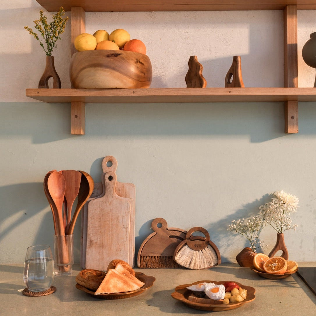 Kitchen counter with wooden shelves, utensils, and decorative items.
