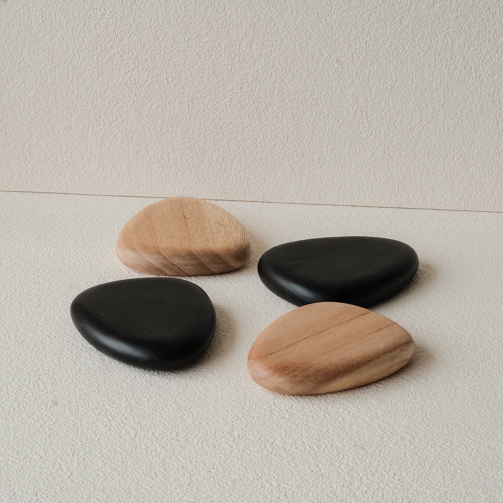 Set of 4 handcrafted Nami Wooden Pebble Coasters – available in Natural and Black Noir finish, wide smooth curved surface, eco-conscious Japandi style