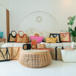 Collection of handbags and baskets displayed in a room with a white sofa and wooden floor.