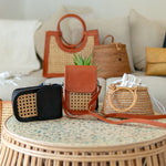 Collection of handbags on a round wicker table with a neutral background