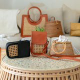 Collection of handbags on a round wicker table with a neutral background