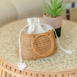 Camilla circle bag with drawstring on a round table with a plant in the background