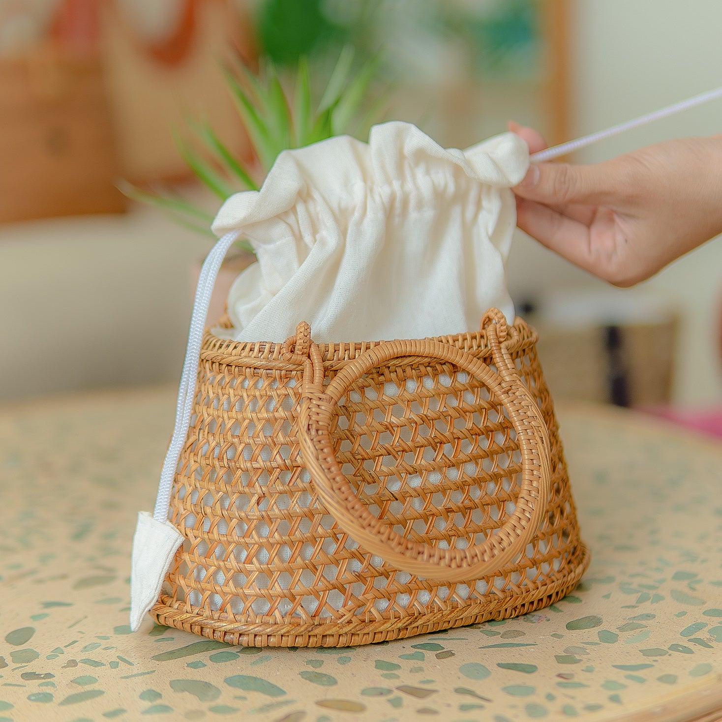 Camilla circle bag with a drawstring lid on a table, with a blurred background