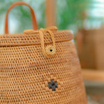 Close-up of Pipa backpack with a decorative knot and button on a blurred background
