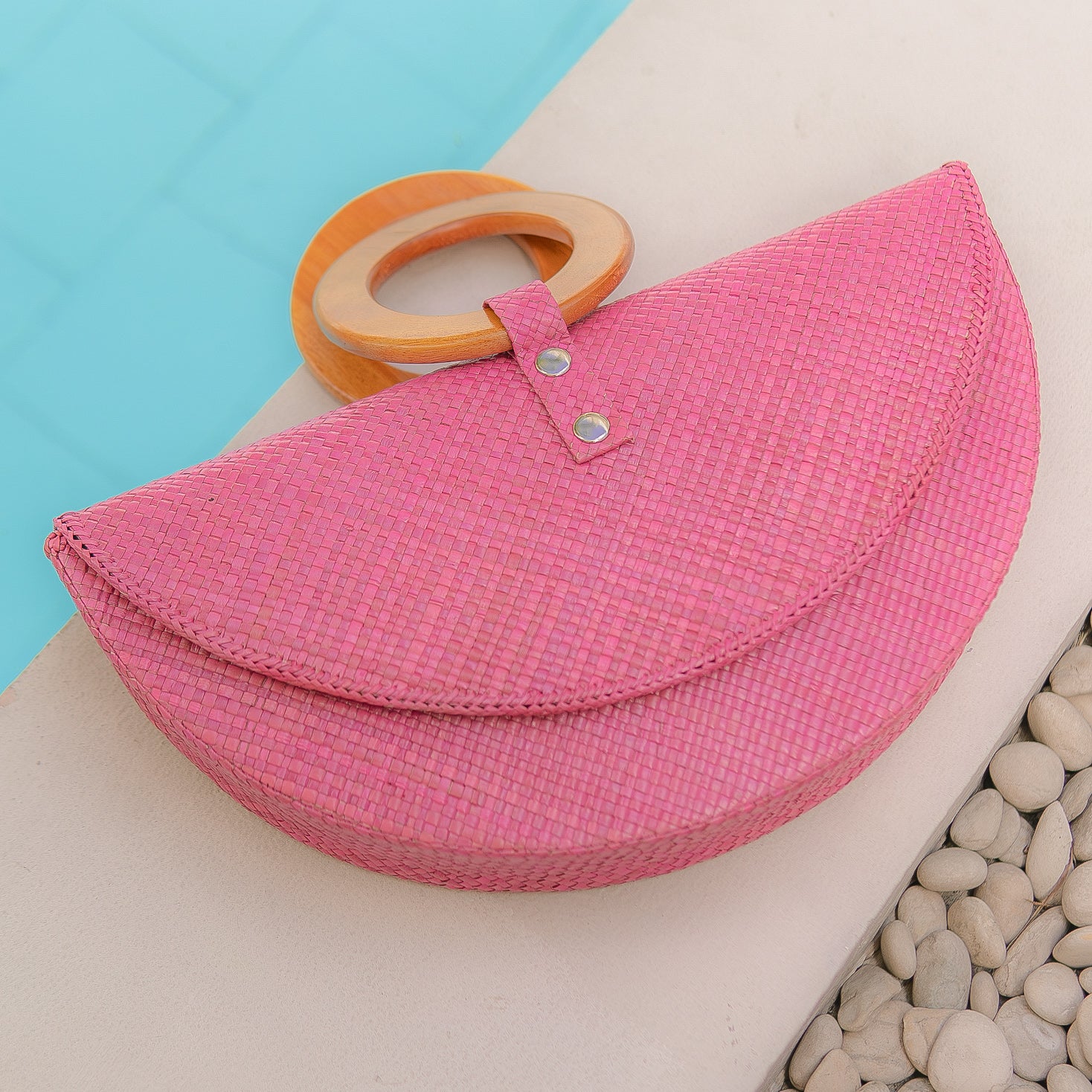 Pink Paloma clutch bag with wood handle by pool