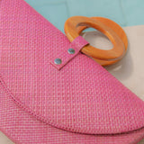 Pink woven bag with orange handles on a light blue background
