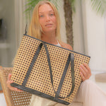 Woman holding a woven handbag with a blurred indoor background