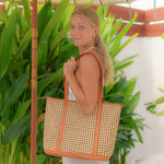 Woman holding a woven handbag with a tropical background