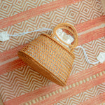 Camilla circle bag with a handle on a patterned fabric background