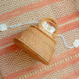 Camilla circle bag with a handle on a patterned fabric background