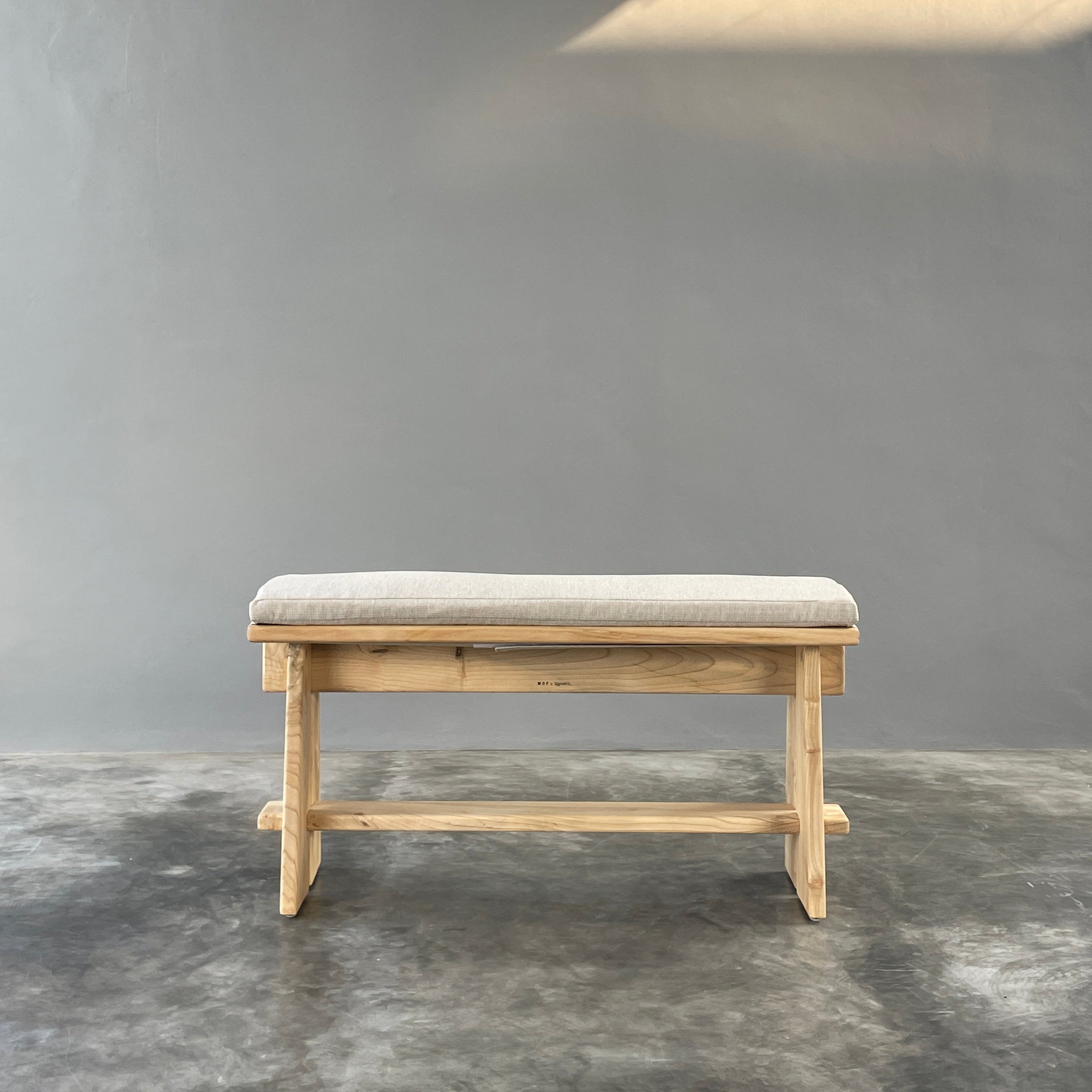 Wooden stool with a cushioned seat on a gray background