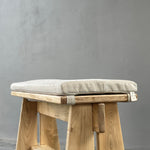 Wooden stool with a cushioned seat on a gray background