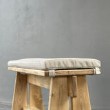 Wooden stool with a cushioned seat on a gray background