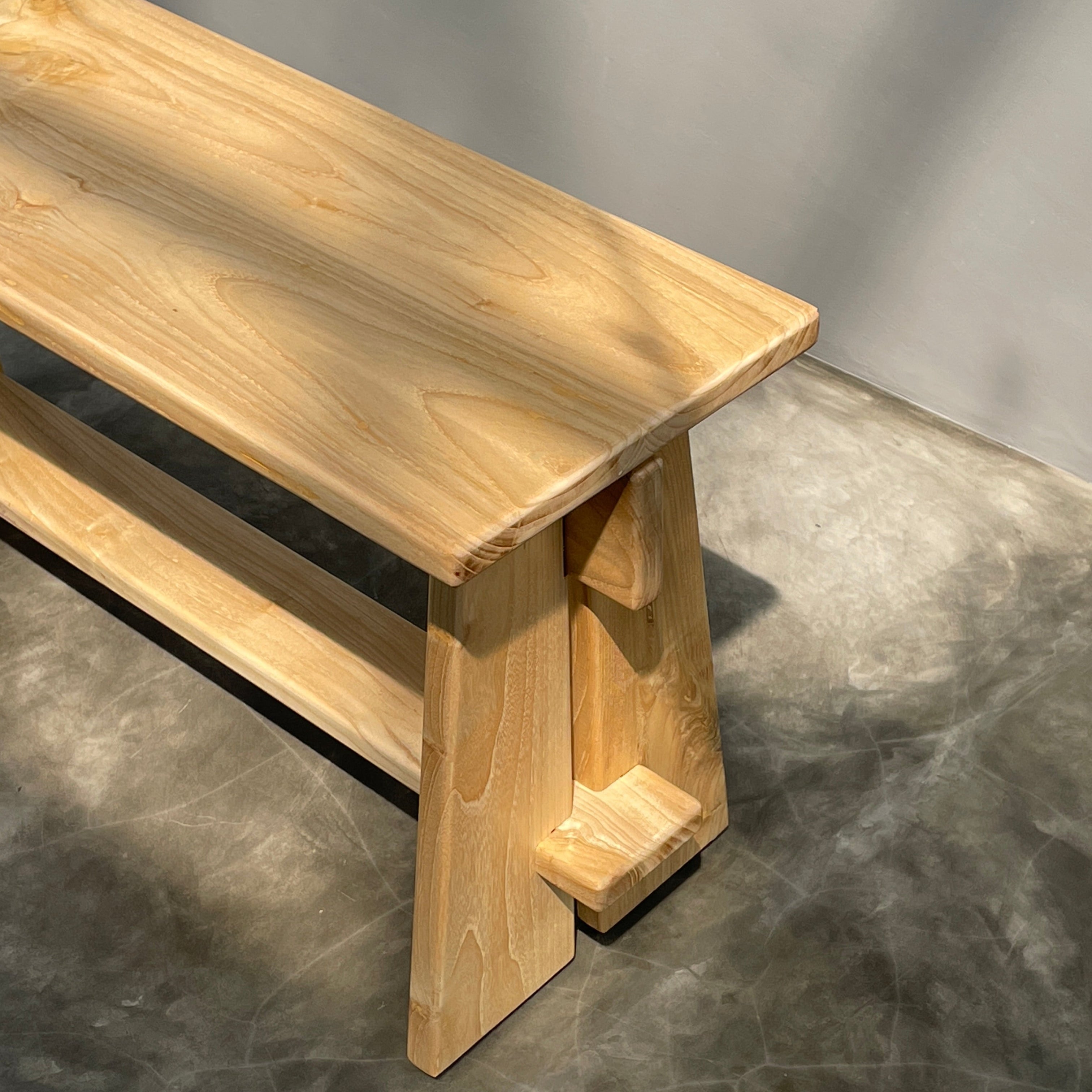 Wooden bench with a modern design on a gray concrete floor