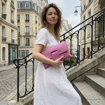 Woman in a white dress holding a pink clutch in an urban setting