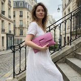 Woman in a white dress holding a pink clutch in an urban setting