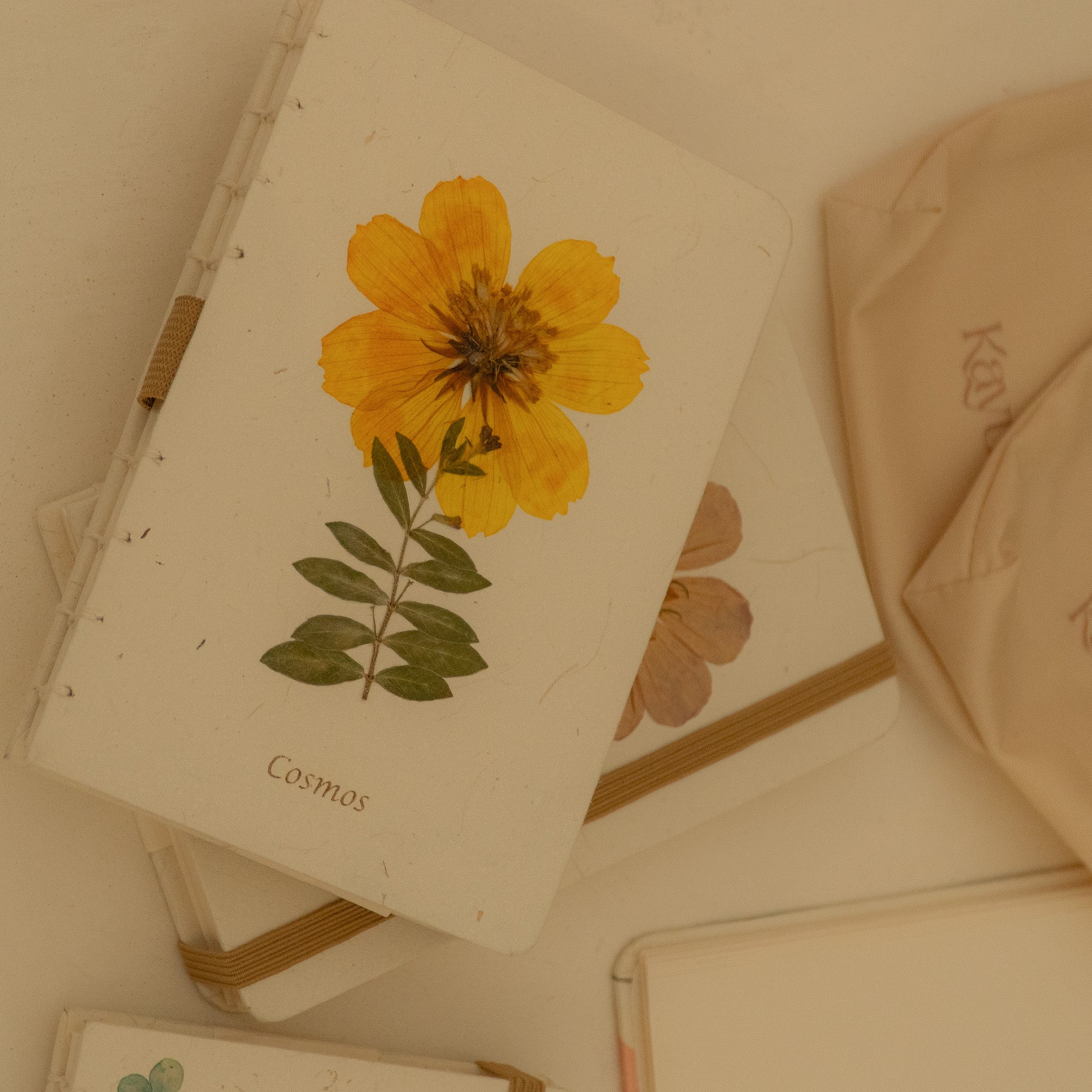 A6 cosmos flower journal with real pressed bloom on the cover, floral pen, and dust bag – colours may vary